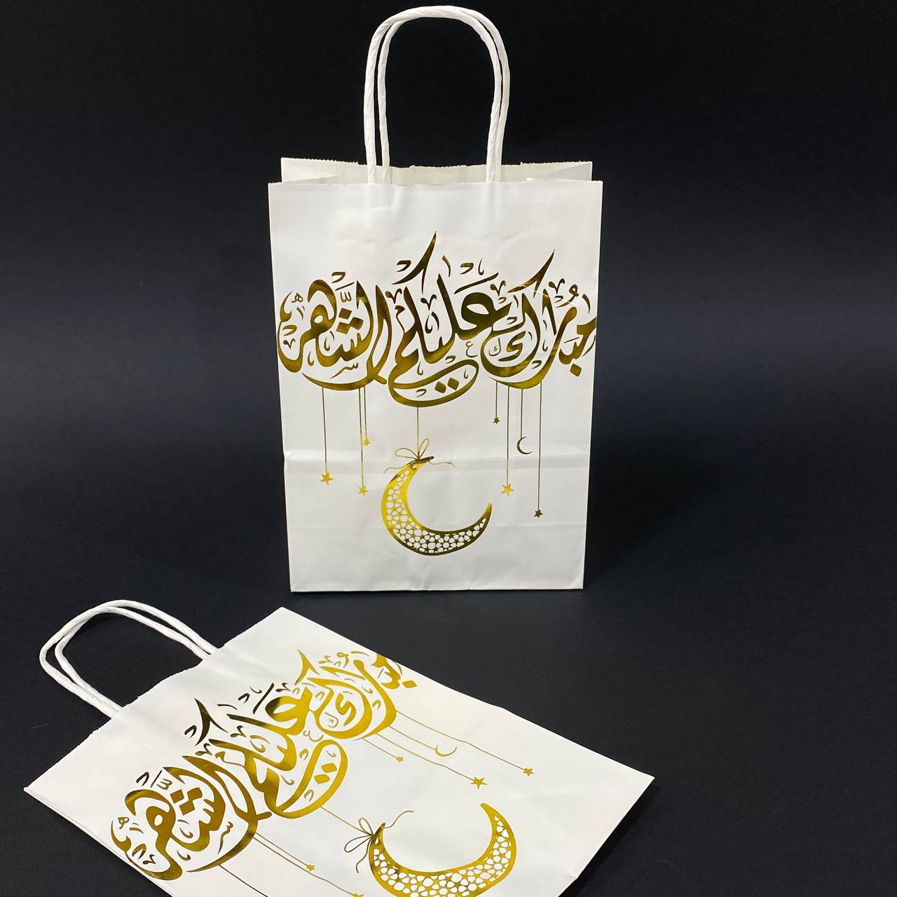 photo_4_2025-02-13_16-42-31 كيس هدايا ورقي ابيض بعبارة ذهبية مبارك عليكم الشهر مع هلال رمضان - الصورة 1